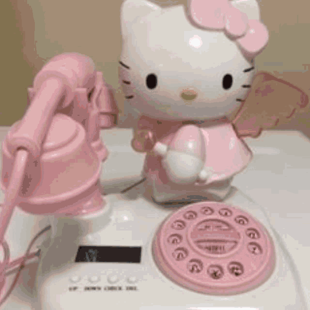 a pink hello kitty telephone is sitting on a table .