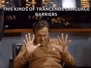 a man in a star trek shirt is sitting in a chair with his hands up in front of his face .