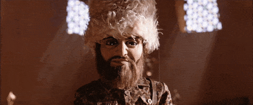 a man with a beard and curly hair is wearing a leopard print shirt