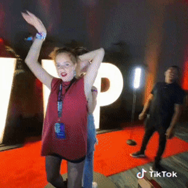 a woman is dancing in front of a sign that says tp on it