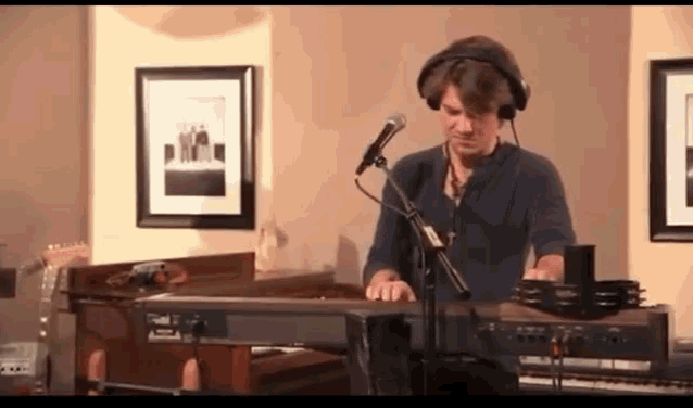 a man wearing headphones is playing a piano and singing into a microphone