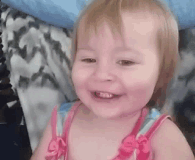 a little girl in a pink and blue dress is smiling .