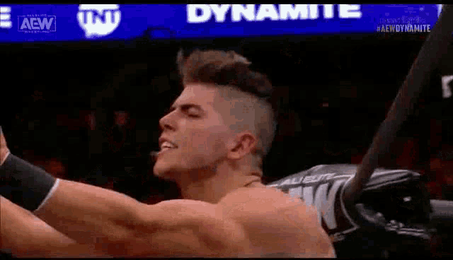 a man without a shirt is holding a bat in his hand while wrestling .