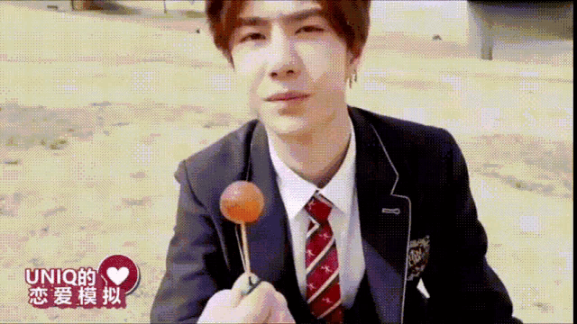 a man in a suit and tie is holding a lollipop with chinese writing on it