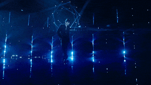 a man in a suit and hat is dancing in a dark room with blue lights