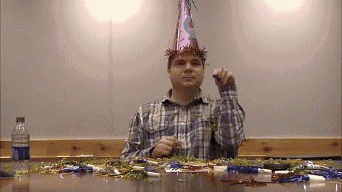 a man wearing a party hat sits at a table with a bottle of water