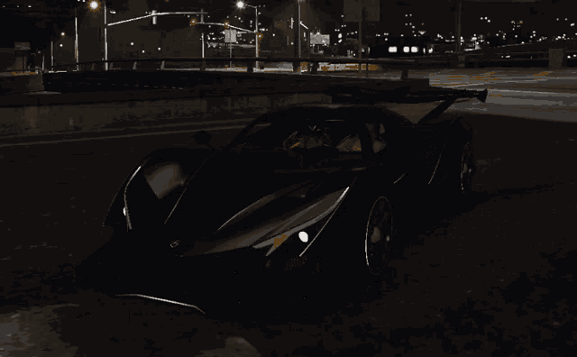 a black car is parked on the side of a road at night