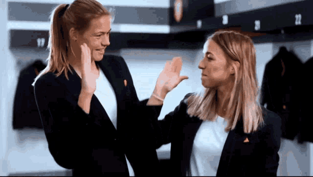 two women high five each other in a locker room