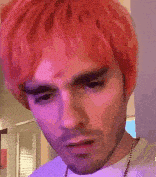 a man with red hair is wearing a purple shirt and a necklace .