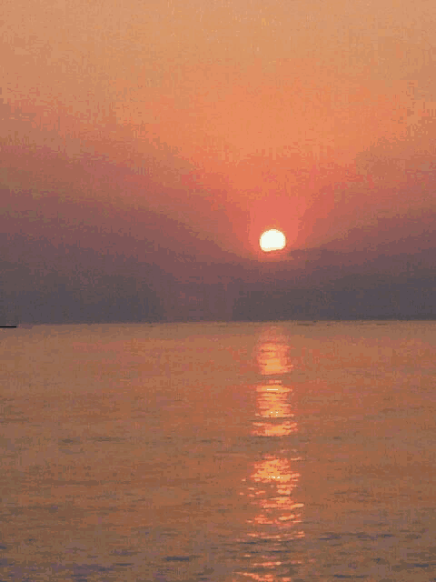 a sunset over a body of water with the sun setting in the distance