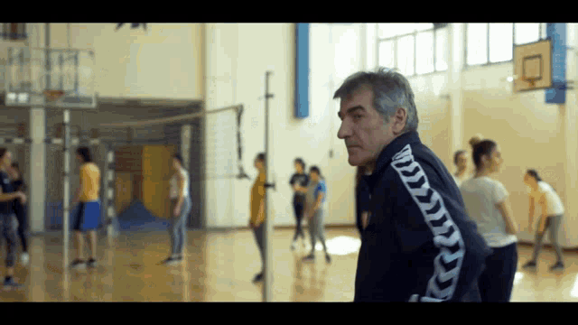 a man wearing a kappa jacket is standing in a gym