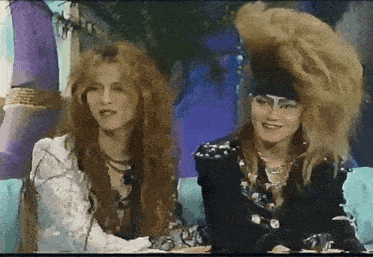 a woman with long red hair is sitting next to another woman