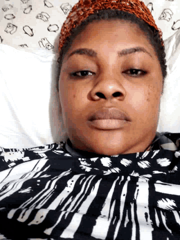 a woman wearing a headband and a black and white shirt laying on a bed