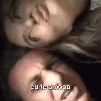a man and a woman are laying on top of each other and the woman is kissing the man 's forehead .