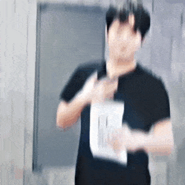 a blurry picture of a man in a black shirt holding a piece of paper in his hand .