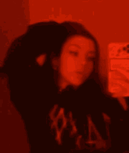 a girl is taking a selfie with her phone in a red light .