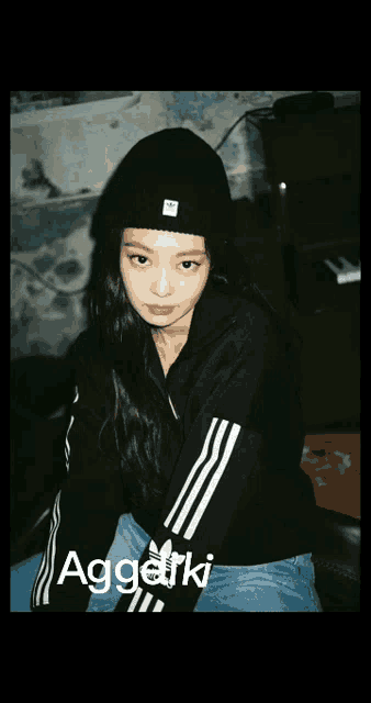 a girl wearing a beanie and a black jacket with the word aggetki on the bottom