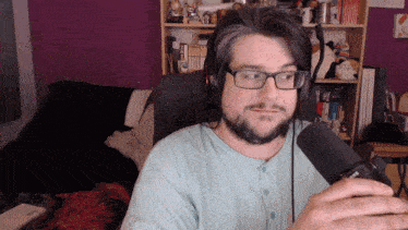 a man wearing glasses and headphones talks into a microphone