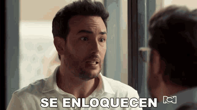 a man in a white shirt is talking to another man and the words se enloquecen are above him