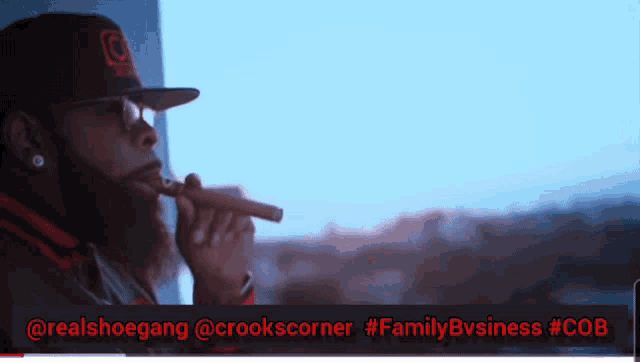 a man in a hat is smoking a cigar in front of a window with the hashtag #familybvsiness