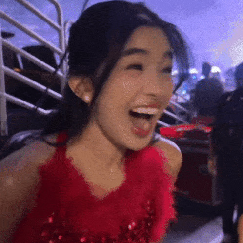 a woman wearing a red dress is laughing with her mouth open