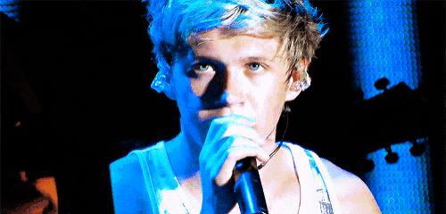 a man is singing into a microphone with a blue background