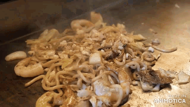 noodles and shrimp are being cooked on a grill with the words made in animatica visible