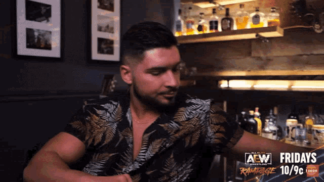 a man is sitting at a bar with a sign that says aew fridays