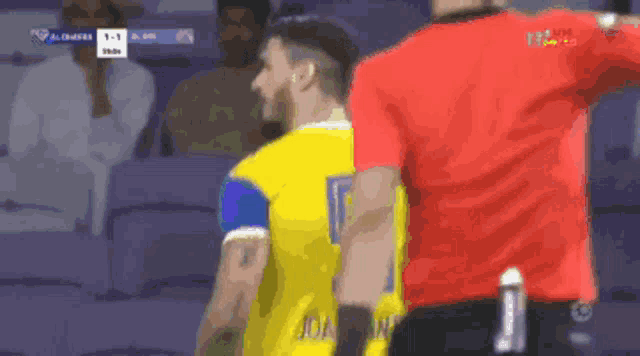 a man in a yellow jersey with the number 9 on it stands next to a man in a red shirt