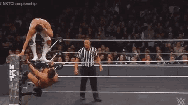 a man is laying on his back in a wrestling ring while another man kicks him .