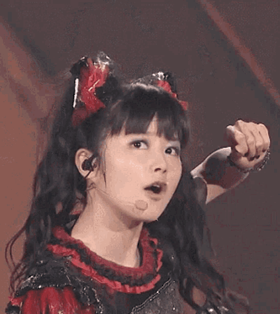 a young girl is singing into a microphone while wearing a black and silver outfit