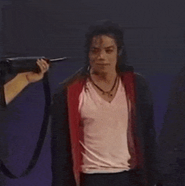 a man in a white shirt and a red jacket is standing on a stage .