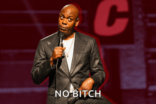 a man in a suit stands in front of a microphone with the words no bitch written below him