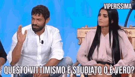 a man and a woman are sitting next to each other and the woman is asking the man a question