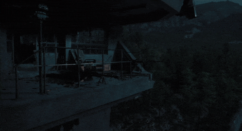 a man holding a sniper rifle on a balcony at night