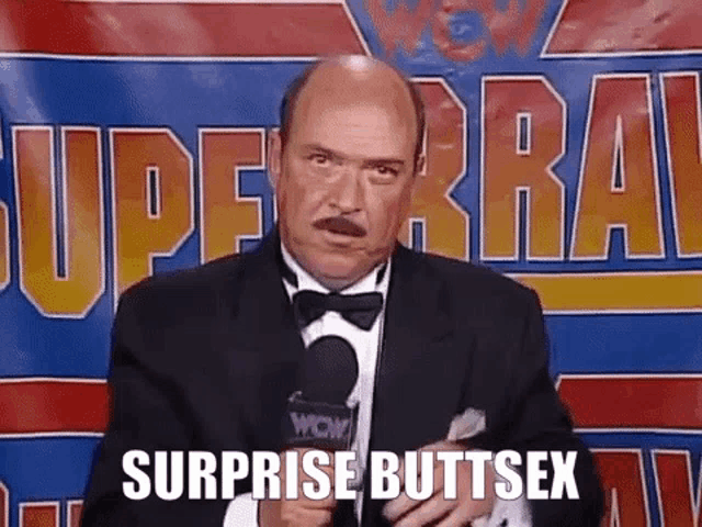 a bald man in a tuxedo and bow tie is talking into a microphone .