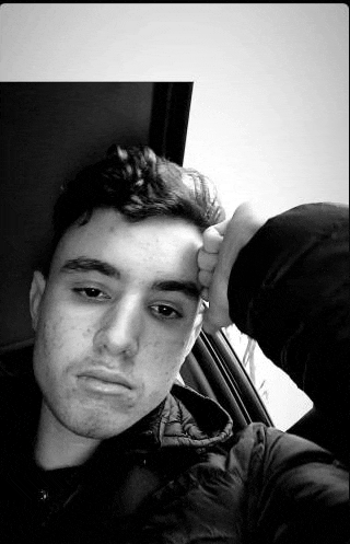 a young man is taking a selfie in a car with his hand on his face .