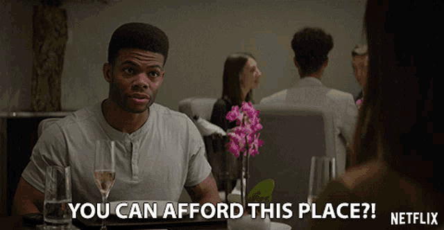 a man sits at a table with a glass of wine and says you can afford this place netflix