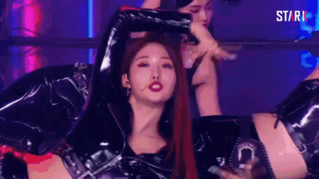 a woman in a black leather suit is dancing on stage .