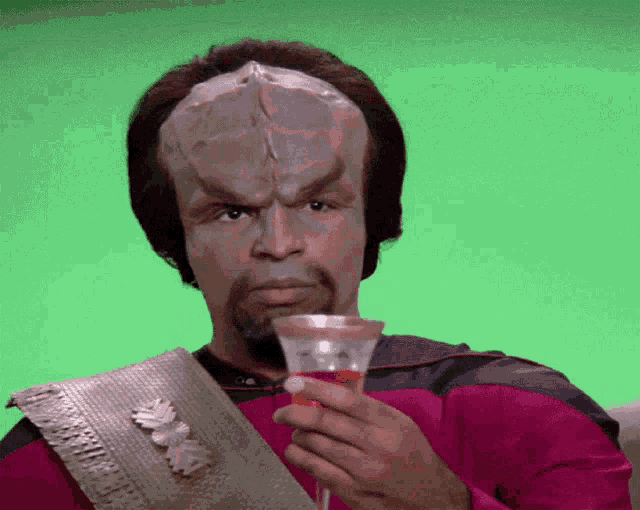a man in a mask holds a glass of wine