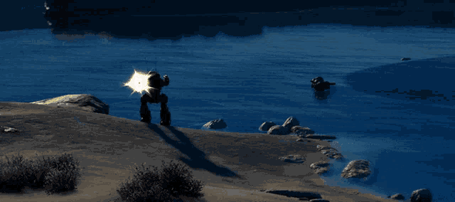a silhouette of a robot standing on top of a sandy hill near a body of water