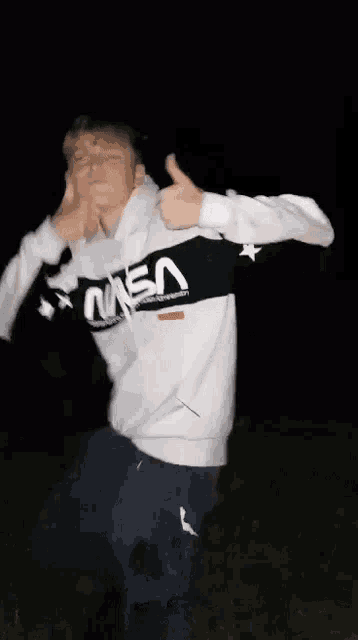 a man in a nasa shirt is dancing in the dark .