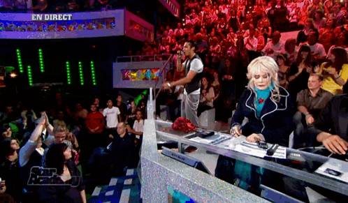 a woman stands in front of a crowd with a sign that says en direct on it