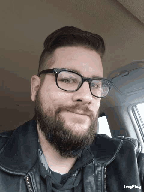 a man wearing glasses and a leather jacket is smiling