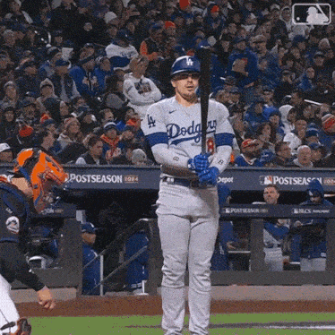 a dodgers baseball player holds a bat in front of a crowd of people