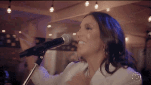 a woman singing into a microphone with a picture of a camera in the background