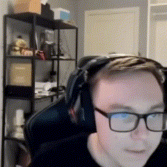 a man wearing glasses and headphones sits in a chair