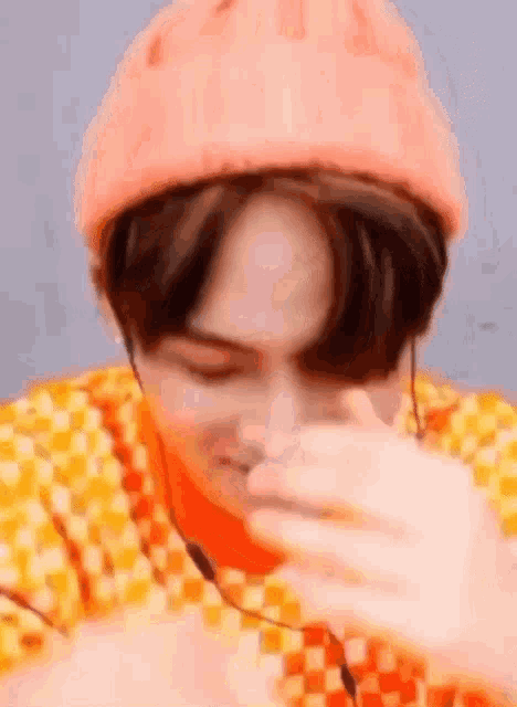 a close up of a person wearing a pink beanie and an orange shirt .