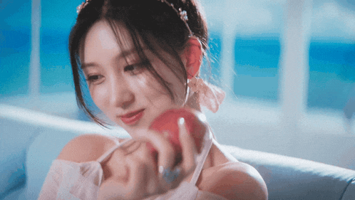 a woman is sitting on a couch holding an apple