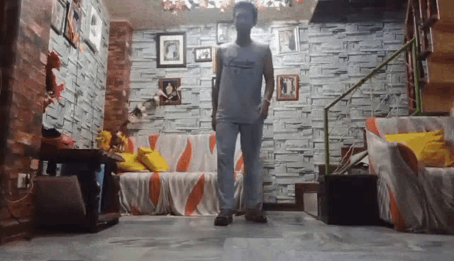 a man standing in a living room with a brick wall